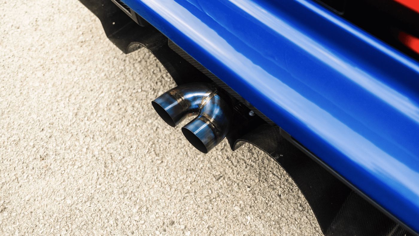 Dual titanium exhaust tips below the blue rear bumper